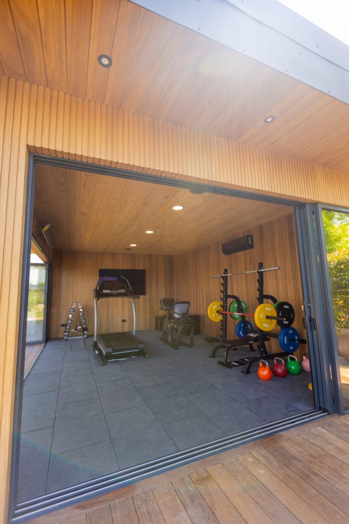 Proiect Enipau sală de sport – spațiu privat de antrenament cu podea din deck Sucupira, riflaj Ayous cu textură caldă și miros subtil de cafea, plafoane exterioare din lambriu Ayous și tavan interior realizat din Pin Radiata selectat pentru luminozitate și rafinament – Poza 3